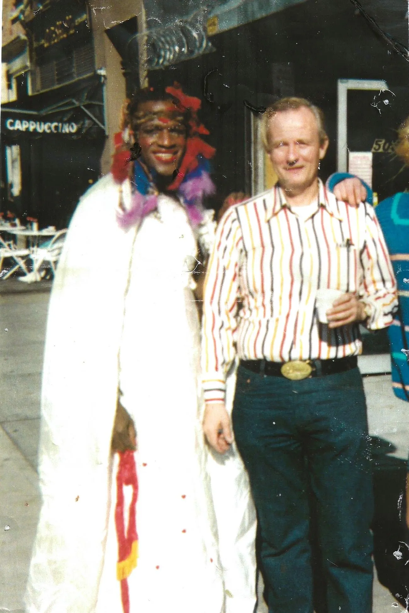 johnson and wicker standing together in a color photograph while johnson wears a long white garment and bright feathers on her head